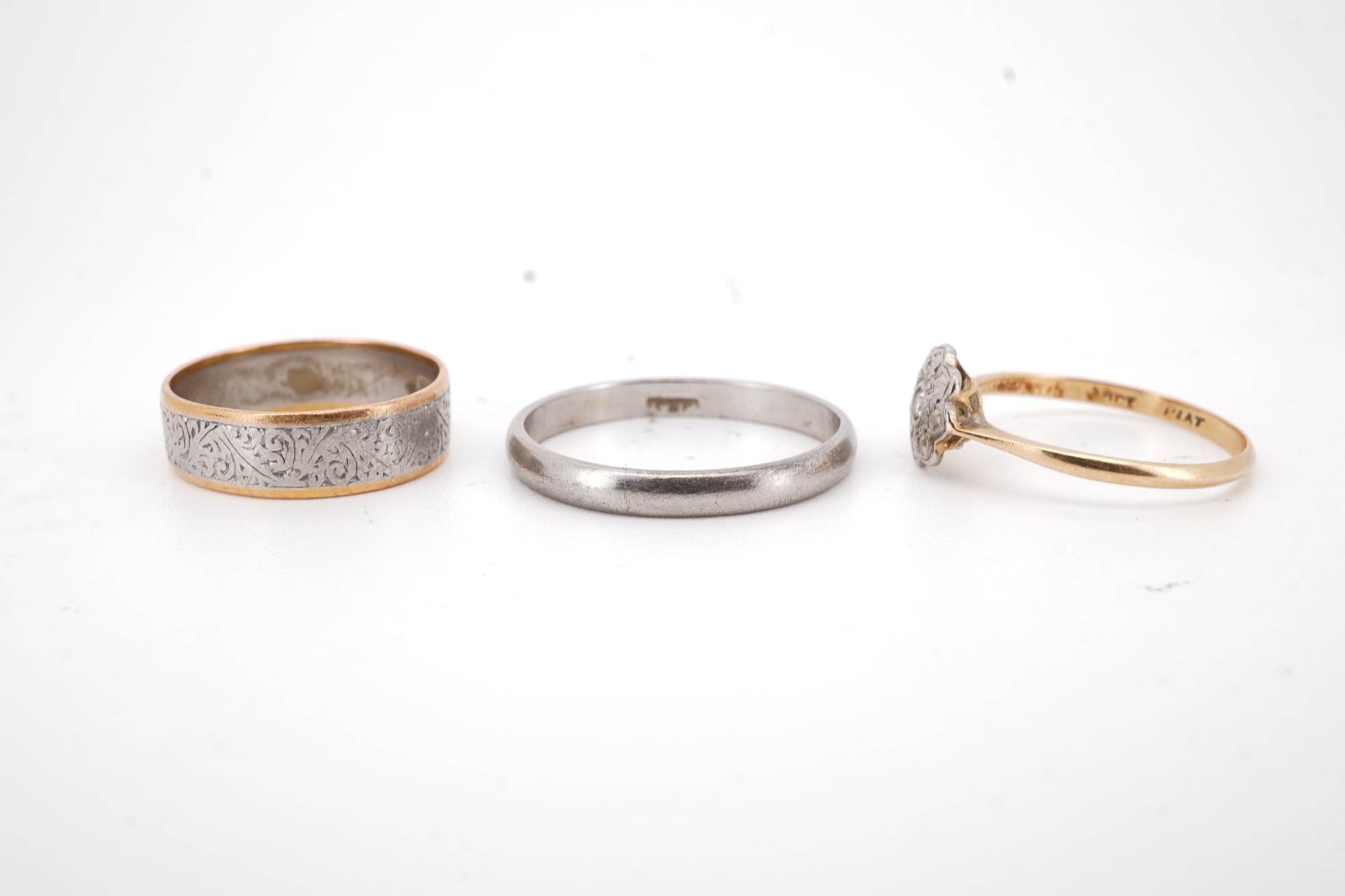 Three rings, comprising: a platinum wedding band, size N1/2, stamped PLAT, gross weight 3 grams; a bicoloured band, size J, stamped PLATINUM 22CT, gross weight 3 grams; and a ring set with a diamond weighing approximatel